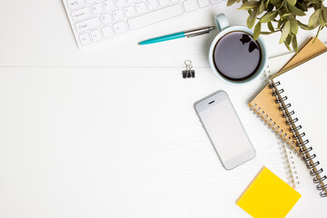 Working space with coffee, pen, phone and notebook on a white table. 