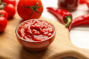 Delicious adjika sauce in bowl and ingredients on table, closeup