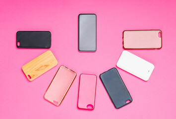 Choice of multicolored plastic back covers for mobile phones on pink background with a smart phone on the side