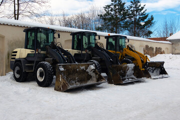 Heavy duty earth movers parked next to each other used to move snow after blizzard. Industrial...