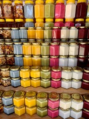There are many jars of organic, natural honey on the counter for sale. Different honey, different colors in plastic cans are ready for sale at the honey fair. Nuts filled with honey. 