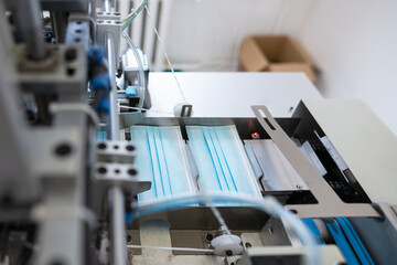Closeup process of medical face masks being made in a factory. Automated machinery making respiratory medical masks in large quantities.