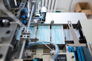 Closeup process of medical face masks being made in a factory. Automated machinery making respiratory medical masks in large quantities.
