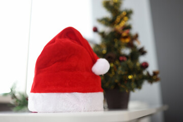 Santa claus hat standing near christmas tree closeup
