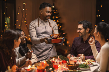 holidays and celebration concept - multiethnic group of happy friends having christmas dinner at home