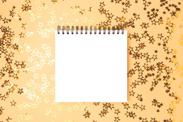 Empty square notebook mockup with glittering stars confetti on a gold background.
