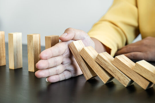 Risk and Strategy in Business, Image of hand stopping falling collapse wooden block dominoes effect from continuous toppled block, prevention and development to stability
