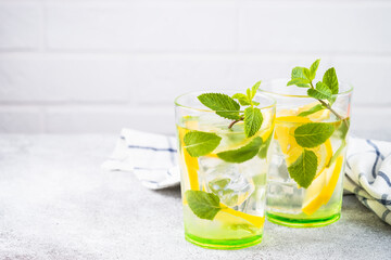 Lemonade in two glasses at white table. Summer drink, traditional refreshment cocktail.