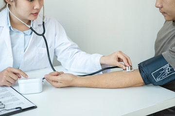 Doctor is checking blood pressure for the patient and using stethoscope to listening heartbeat