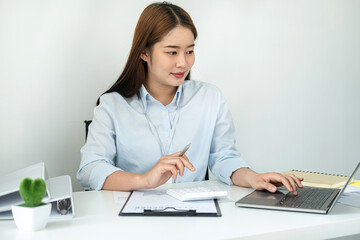 Woman office worker reading and typing business project report on laptop after that taking note of information
