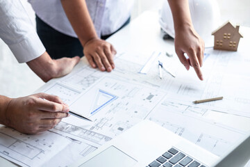 Construction engineering or architect discuss a blueprint while checking information on drawing and...