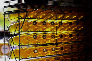 Glass bottles filled with bright yellow apple juice in a rack