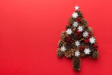 Christmas tree made from natural cones on colored background, view from above. New Year minimal concept with copy space