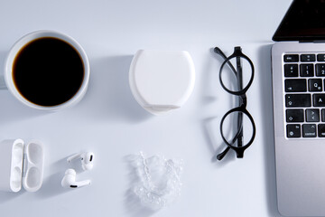 Isolated invisible aligner braces composed with laptop, coffee, and ear phones concept.