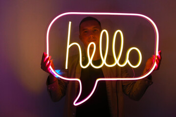 Handsome young man holding pink and yellow neon sign hello. Trendy style. Neon sign. Custom neon....