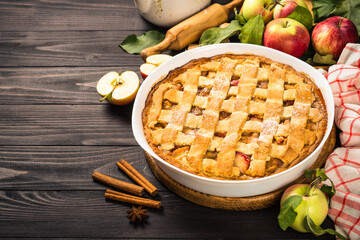 traditional Apple pie with ginger and cinnamon at dark wooden table. Traditional autumn baking.