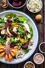  Beetroots salad with feta cheese, walnuts and tangerines on wooden background
