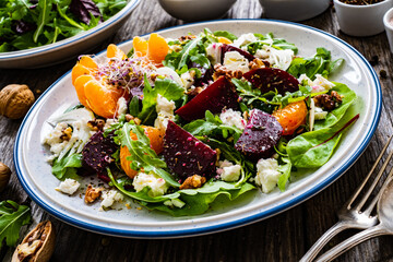  Beetroots salad with feta cheese, walnuts and tangerines on wooden background
