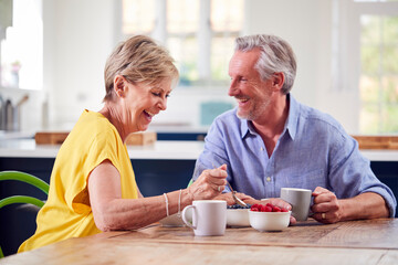 Retired Couple Sitting Around Table At Home Having Healthy Breakfast Together