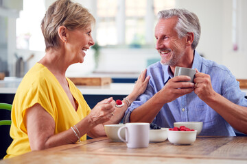 Retired Couple Sitting Around Table At Home Having Healthy Breakfast Together