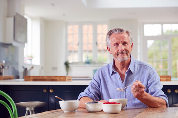 Senior Man Sitting Around Table At Home Having Healthy Breakfast