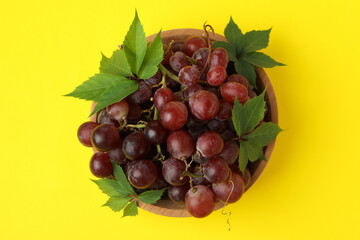 Bowl ripe grape on yellow background, top view