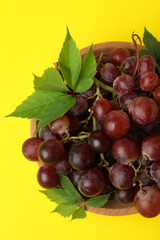 Bowl ripe grape on yellow background, top view