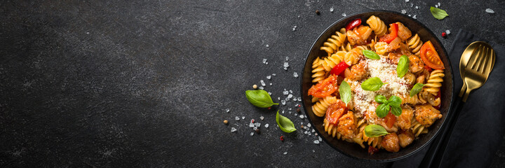 Pasta chicken with vegetables. Top view at black table.