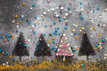 Ein von vier süßen Kuchenstücken in der Reihe dekoriert als Christbaum mit Zuckerperlen, Sternen...
