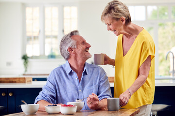 Retired Couple Sitting Around Table At Home Having Healthy Breakfast Together