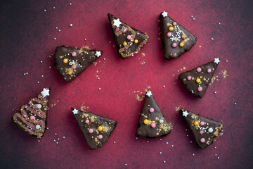 Acht Stück Schokoladengebäck als Christbäume dekoriert mit Zuckerperlen, Sternen aus Zucker auf...