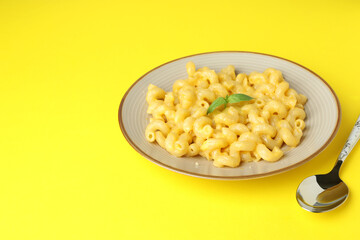Plate with macaroni and cheese on yellow background