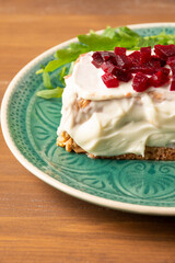 Top view of blue plate with cod pudding with mayonnaise, beetroot and arugula on wooden table, vertical