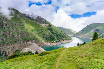 Fototapeta na wymiar Beautiful summer panorama of the mountain lake in Vaujany, France. Cloudy view in the French Alps, Europe. Scenery landscape of high plateau.