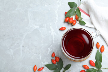 Flat lay composition with aromatic rose hip tea on light grey marble table. Space for text