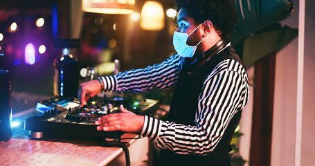 Fototapeta na wymiar African dj playing music at cocktail bar outdoor while wearing face safety mask - Soft focus right
