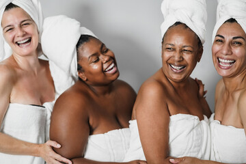 Multigeneration women with diverse skin and body laughing together while wearing body towels -...