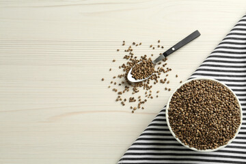 Ceramic bowl with chia seeds on white wooden table, flat lay and space for text. Cooking utensils