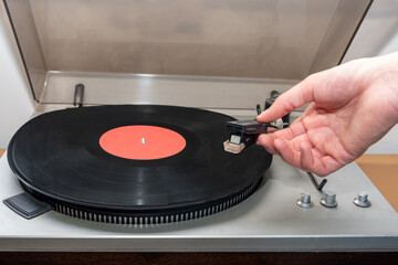 Hand turning on stereo turntable analog retro vintage. An old-fashioned plastic turntable playing a music track