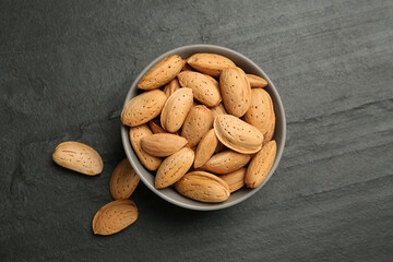 Ceramic bowl with almonds on black table, flat lay. Cooking utensil