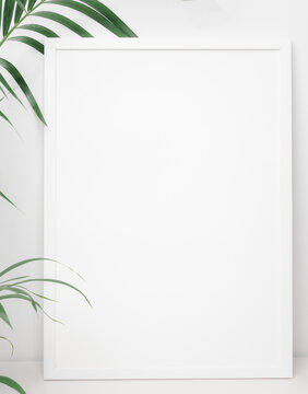 White poster frame decpration with green palm leaf over white wall background,copy space for your design