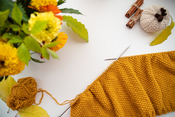 Top view knitting of yellow yarn on a white background. Concept autumn and hand knitting, needlework at home.