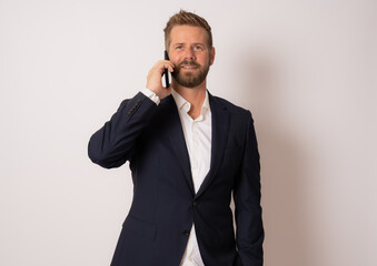 Young smiling business man talking on the phone over isolated background.