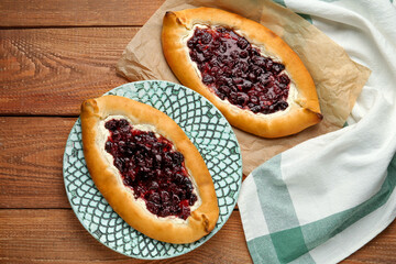 Delicious sweet cottage cheese pastries with cherry jam on wooden table, flat lay