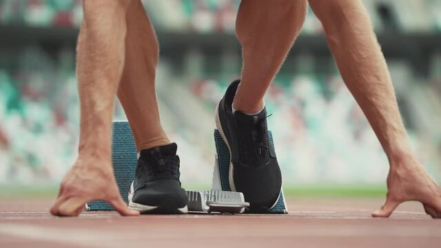 Man sprinter is preparing for the start of a training run in short-distance, professional track runner at a stadium, a tense moment, handheld.