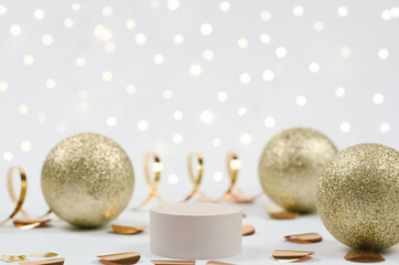 Christmas scene for showcasing cosmetic products. Beige plinth for product demonstration on a white festive background. Podium with New Year's decor, with golden balls, confetti and garland lights