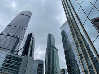 Obraz premium Facade of modern skyscraper with glass walls. From below of contemporary tall skyscraper with glass walls against cloudy sky in downtown
