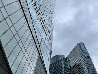 Facade of modern skyscraper with glass walls. From below of contemporary tall skyscraper with glass walls against cloudy sky in downtown