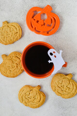 Breakfast or morning for halloween holiday, homemade pumpkin shaped cookies and bakeware cutting dish with a cup of coffee on concrete background