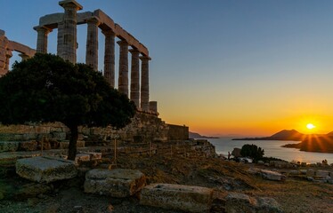 Fototapeta na wymiar Cloudless sunset behind the mountains, with the sea. There is a Greek temple in the picture.